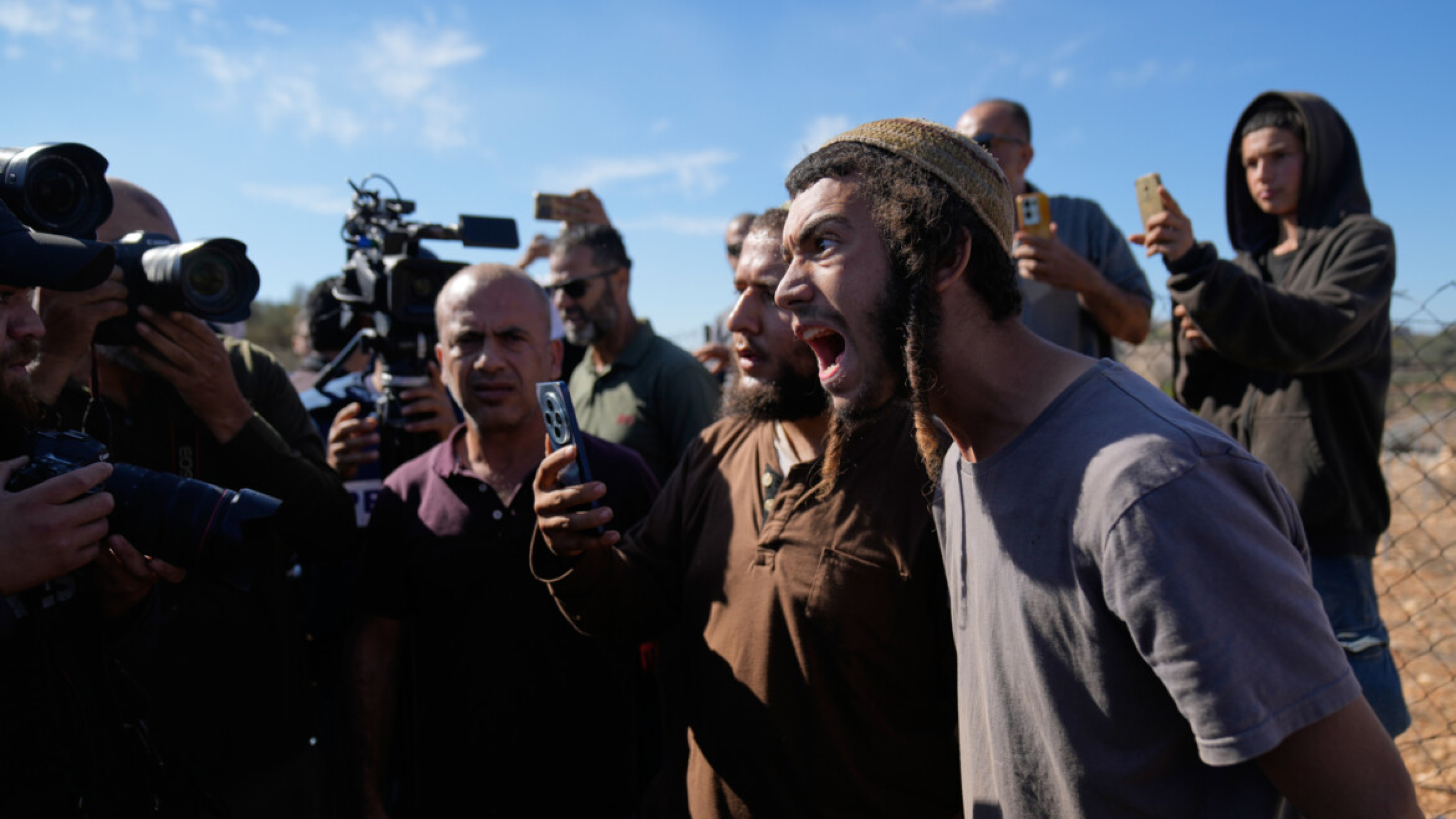Coloni israeliani fotografano attivisti stranieri e contadini mentre tentano di ostacolare la raccolta delle olive da parte dei palestinesi (AP Photo/Nasser Nasser)
