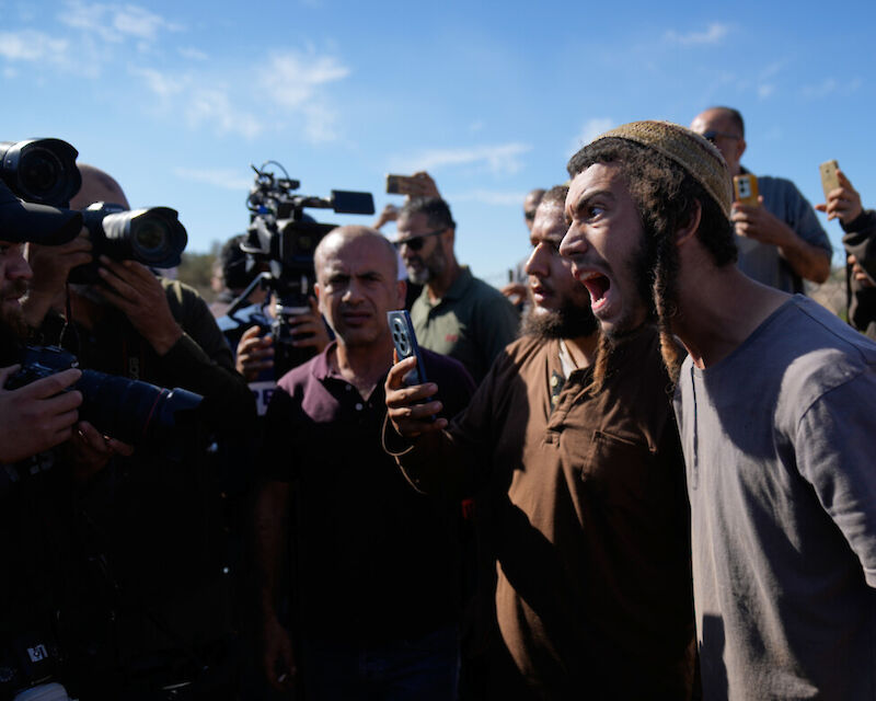 Coloni israeliani fotografano attivisti stranieri e contadini mentre tentano di ostacolare la raccolta delle olive da parte dei palestinesi (AP Photo/Nasser Nasser)