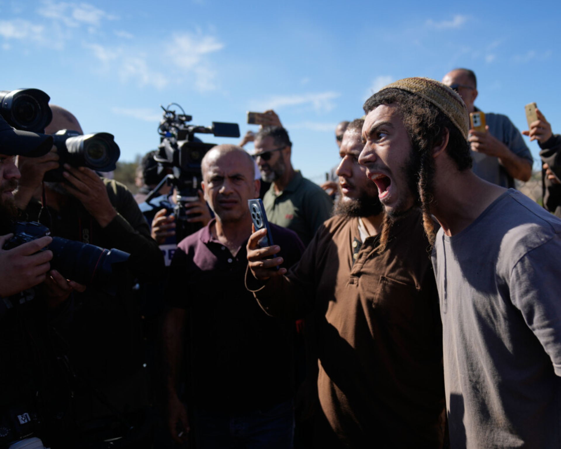 Coloni israeliani fotografano attivisti stranieri e contadini mentre tentano di ostacolare la raccolta delle olive da parte dei palestinesi (AP Photo/Nasser Nasser)